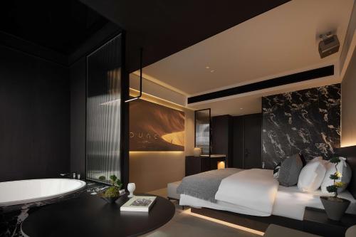 a bedroom with a bed and a tub and a sink at 成都s恩季酒店春熙路太古里店 in Chengdu