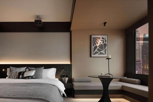 a bedroom with a bed and a table and a window at 成都s恩季酒店春熙路太古里店 in Chengdu
