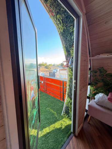 a door to a balcony with a view of a yard at Beehouse TinyGreen Jacuzzi Opcional in Villa Alemana