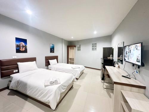 ein Schlafzimmer mit zwei Betten und einem Flachbildfernseher in der Unterkunft ภูมิพิมานเฮ้าส์ in Udon Thani