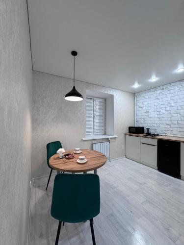 Una habitación con una mesa y sillas y una cocina. en R-home, микрорайон Юбилейный 19, en Kostanái