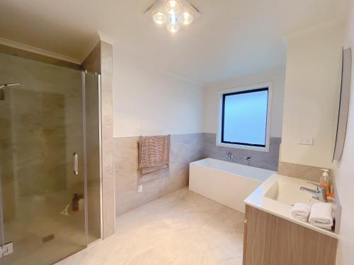 ein Badezimmer mit Badewanne, Waschbecken und Dusche in der Unterkunft Rotorua Sunshine Brand New 4 Bedroom house in Rotorua