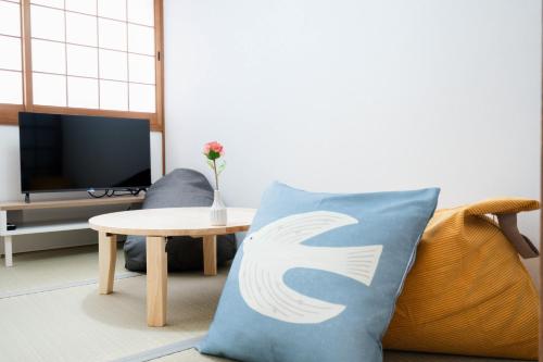 a living room with a couch with a pillow with a symbol at LN25三宮徒歩8分の2DKハウスSwallowMaisonet in Kobe
