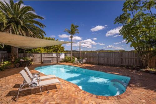 a swimming pool with two chairs and a umbrella at Bermagui Coastal Hideaway - Pet Friendly in Bermagui