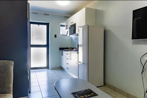 Una pequeña cocina con nevera y mesa. en Grace Villas 7, en East London