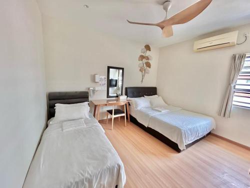 a bedroom with two beds and a desk in it at 8 mins driving to TC Beach at Holiday Guest House in Kuantan