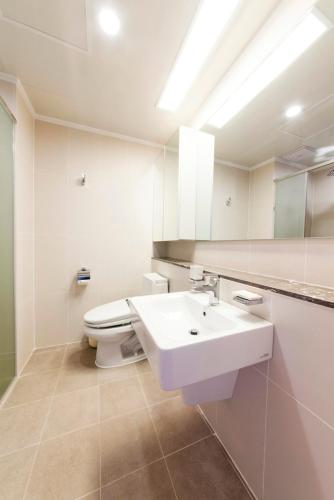 a white bathroom with a sink and a toilet at Kumho Jeju Resort in Seogwipo
