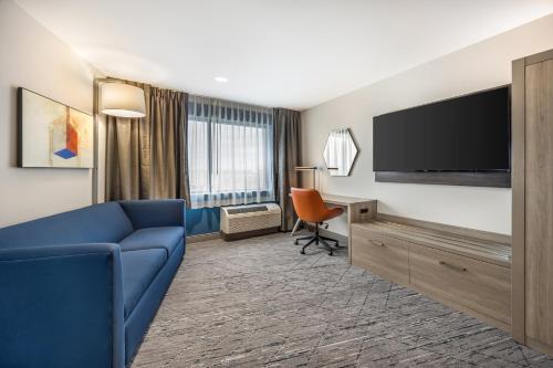 a hotel room with a blue couch and a flat screen tv at Holiday Inn Express & Suites Nashville West End - Univ Area by IHG in Nashville