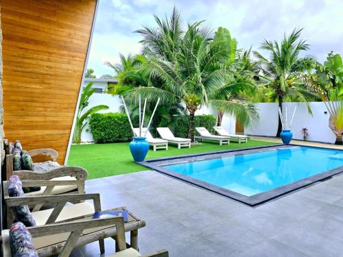 a pool with chairs and palm trees in a backyard at CYAN Jasmine Pool Villa - Fisherman's Village in Bophut