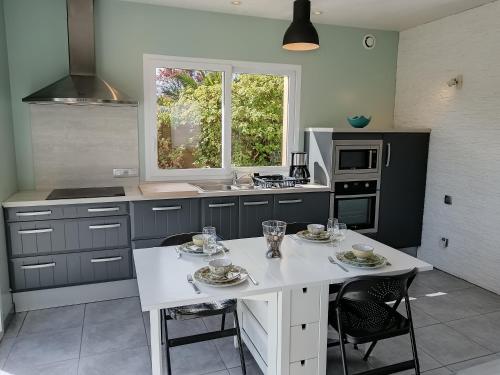 une cuisine avec une table blanche et des chaises dans l'établissement Santec Roscoff maison 500m mer Finistère Bretagne, à Santec