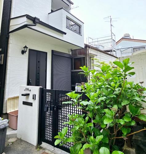 a white house with a gate and a refrigerator at Hanen半園 in Osaka