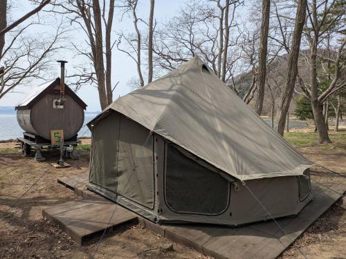 a tent sitting on a wooden platform next to a barn at Roots inawashiro Lake Area in Sekiwaki