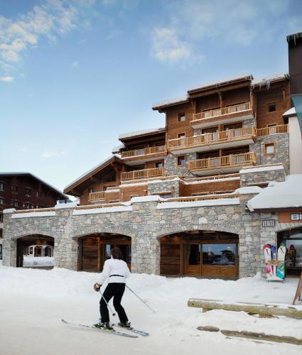 a person on skis in the snow in front of a building at CGH Résidences & Spas La Ferme Du Val Claret in Tignes