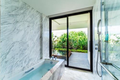 a bathroom with a large tub and a glass window at Halekulani Okinawa in Onna