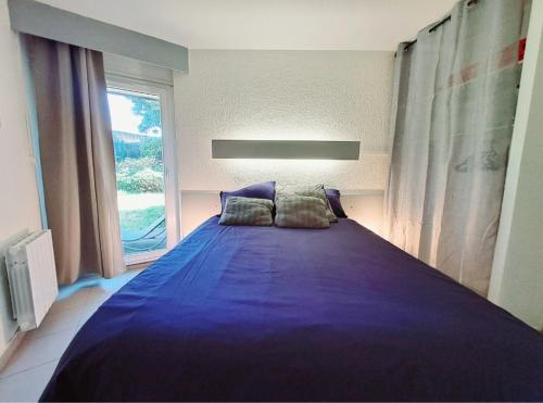 - une chambre avec un grand lit violet et une fenêtre dans l'établissement Maisonnette de vacances avec jardin clos, à Guidel