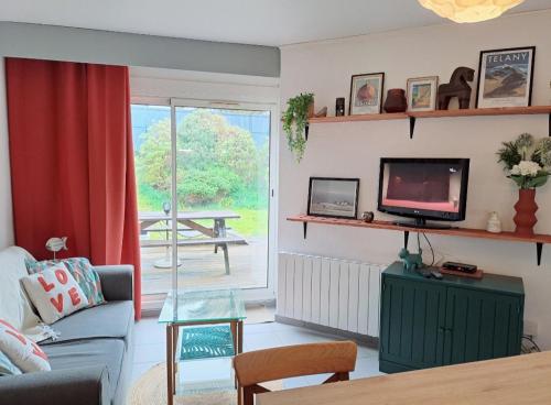 un salon avec un canapé et une télévision dans l'établissement Maisonnette de vacances avec jardin clos, à Guidel