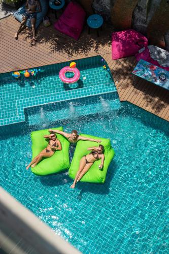 two women laying on a raft in a swimming pool at Mad Monkey Phuket in Patong Beach