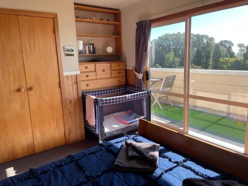 a bedroom with a bed and a large window at 49 on Jans Beach Break in Oakura