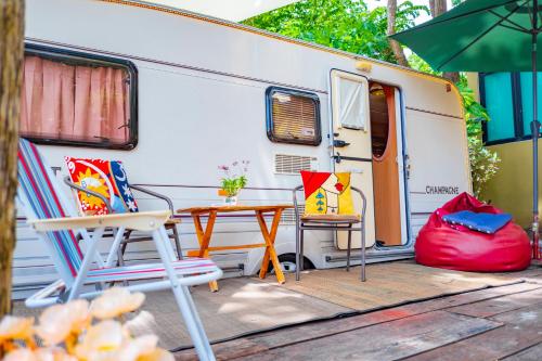 an rv with chairs and a table and an umbrella at TREX Buriram Boutique Hotel in Buriram