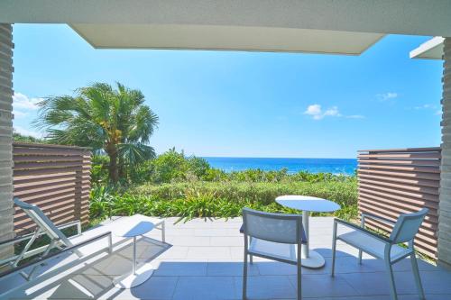 a patio with chairs and a table and the ocean at Halekulani Okinawa in Onna