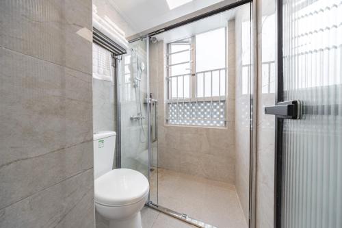 a bathroom with a toilet and a glass shower at Shenzhen Gangxiahui Executive Apartment Futian Convention and Exhibition Center Branch in Shenzhen