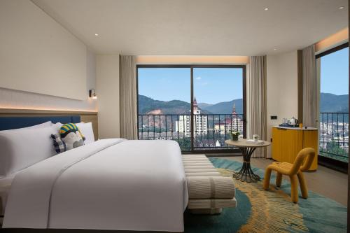 a bedroom with a large bed and a balcony at voco Xishuangbanna Gaozhuang by IHG in Jinghong