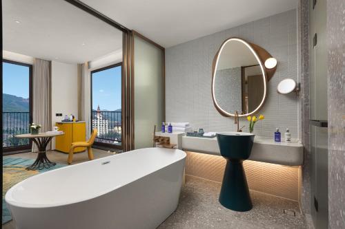 a bathroom with a tub and a mirror at voco Xishuangbanna Gaozhuang by IHG in Jinghong