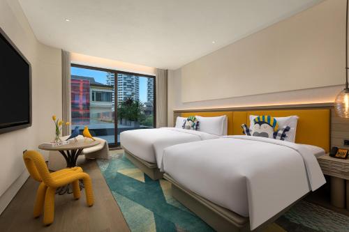 a hotel room with two beds and a window at voco Xishuangbanna Gaozhuang by IHG in Jinghong