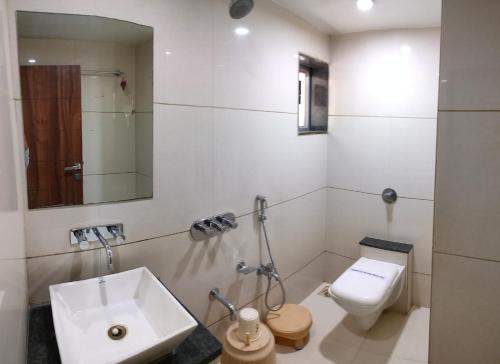 ein weißes Badezimmer mit Waschbecken und Toilette in der Unterkunft Hotel Zenith in Surat