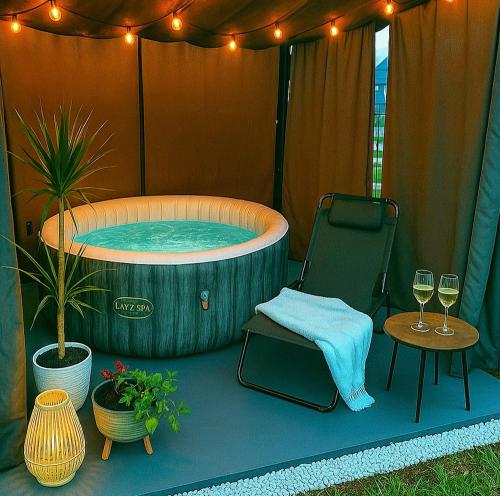 a hot tub in a tent with two glasses of wine at Apartamenty Cudne Manowce in Łeba