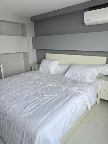 a bedroom with a white bed with a night stand at Hua Hin - My pleasure in Hua Hin