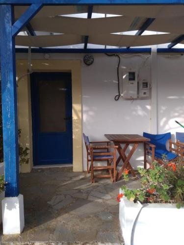a patio with a table and chairs and a blue door at Kouvaras Apartments in Kýthira