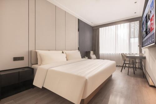 a bedroom with a large white bed and a table at Atour X Hotel Tianjin Binhai Airport Free Trade Zone in Tianjin