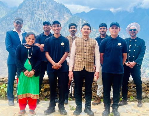 a group of people posing for a picture in front of a mountain at Faraway Cottages, Auli in Joshīmath