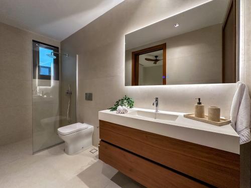 a bathroom with a sink and a toilet and a mirror at Marina Garden Cap Cana by Beach Homes Punta Cana in Punta Cana