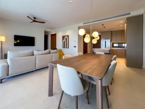 a dining room and living room with a wooden table and chairs at Marina Garden Cap Cana by Beach Homes Punta Cana in Punta Cana