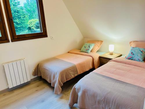 deux lits dans une chambre avec une fenêtre dans l'établissement Le Cottage aux portes de Deauville, à Bonneville-sur-Touques