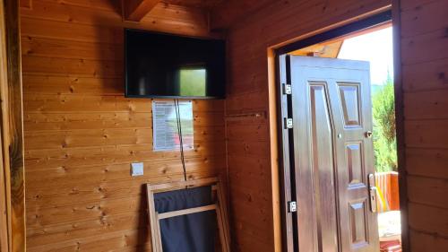 a room with a door and a tv on a wall at Domki nad Soliną CZARNY KOT 509-797-777 in Solina