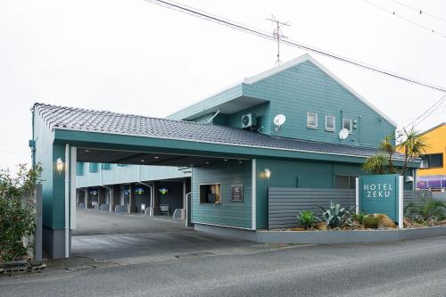 a blue hotel building with a parking garage at HOTEL ZEKU yoshida in Yoshinaga