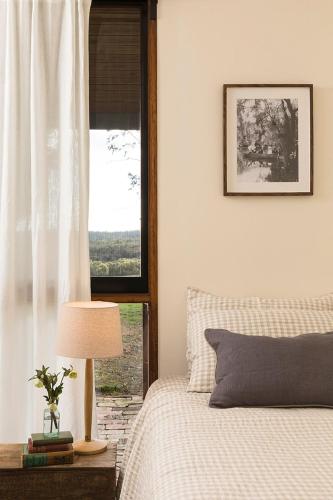 a bedroom with a bed with a lamp and a window at Mingara Park Cottage in Scotsburn