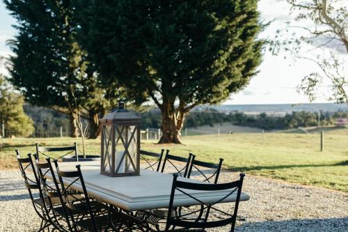 a table with chairs and a lantern on top of it at Mingara Park Cottage in Scotsburn