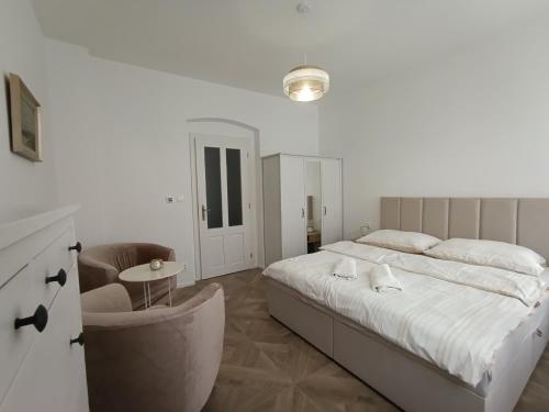 a white bedroom with a bed and a chair at Rezidence Valcha in Sušice
