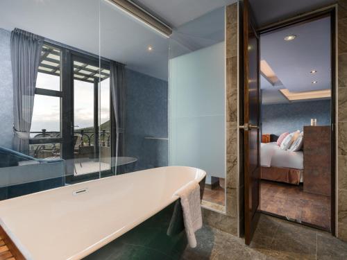 a bathroom with a bathtub and a bedroom at Daybreak in Jiufen