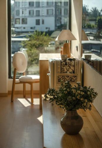 a living room with a table and a vase with a plant at The White Courtyard in Dali