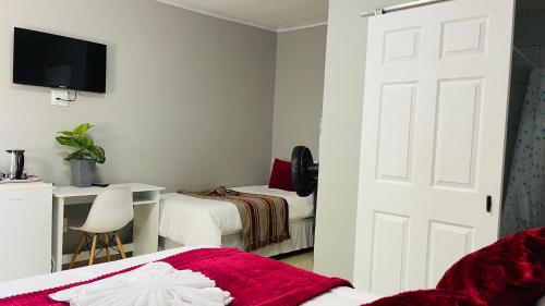 a bedroom with two beds and a desk and a door at Maita Guest in Cape Town