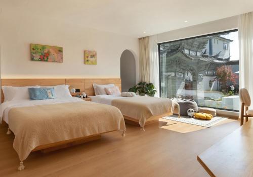 a bedroom with two beds and a large window at The White Courtyard in Dali