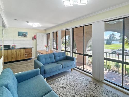 a living room with two blue couches and a kitchen at Charming 2-Bed Apartment with Bay Views in Batemans Bay