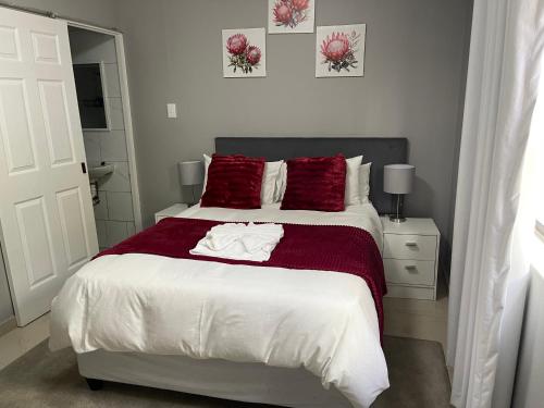 a bedroom with a large bed with red pillows at Maita Guest in Cape Town