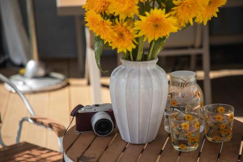 a vase with yellow flowers and a camera on a table at The White Courtyard in Dali