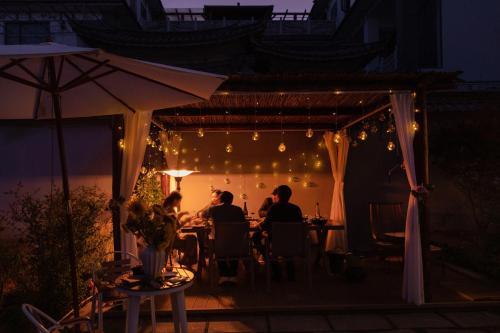 a group of people sitting at a table under a tent at night at The White Courtyard in Dali